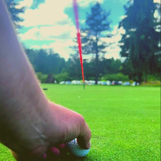 Putt Line Two-Way Putting Practice System Breaking Putt Set Up Instructional Video with string line set up and golfer putting towards a visual rubber puck that is set up on the slope of a practice green. 
